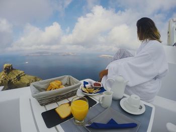 Rear view of woman sitting at cafe against sky