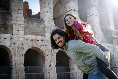 Young couple having fun traveling in rome. the man carries his girlfriend on his back.