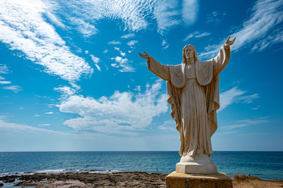 Statue by sea against sky