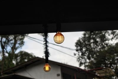 Low angle view of illuminated light bulb hanging from ceiling