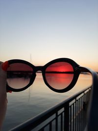 Close-up of sunglasses against sky during sunset