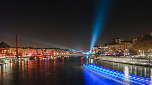 Illuminated bridge over river with city in background