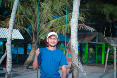 Portrait of smiling young man standing against trees