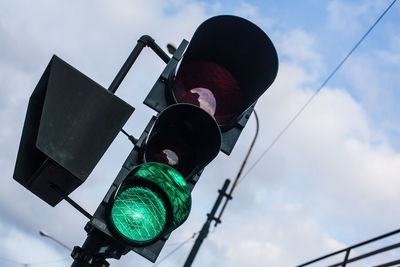 Low angle view of stoplight against cloudy sky