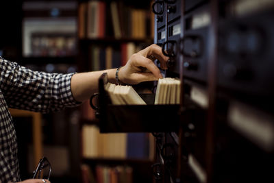 Cropped hand of woman taking library cards from drawer