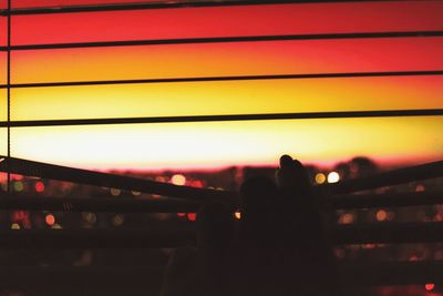 Silhouette person against illuminated orange sky