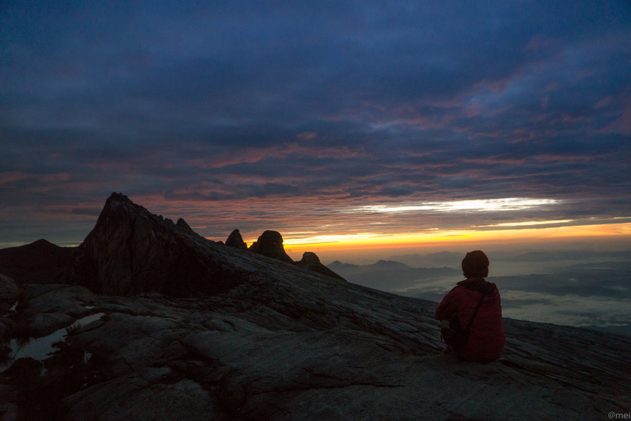 PEOPLE ON ROCK AGAINST ORANGE SKY