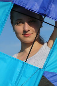 Portrait of young woman looking through kite