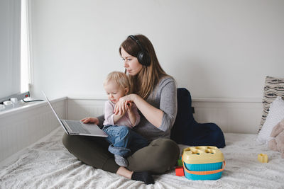 Caucasian mother with toddler baby working on laptop from home. workplace of freelancer