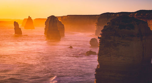 Rock formation in sea against sky during sunset