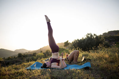 Woman relaxing on field against clear sky