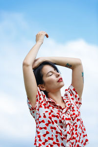 Young woman looking away against sky