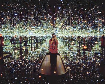 Midsection of woman standing by illuminated lights at night