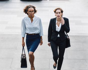 Businesswomen walking on steps against wall