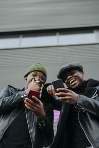 Black friends using smartphones on street