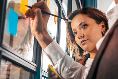 Portrait of young woman looking through window