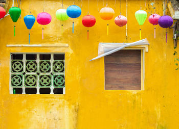 Low angle view of multi colored balloons hanging on wall of building