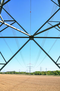 Electricity pylon on field against clear blue sky