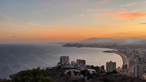 High angle view of cityscape by sea against sky during sunset