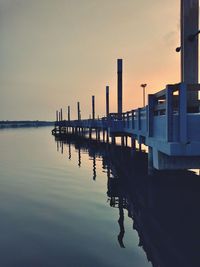 Pier on sea against sky during sunset