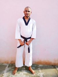 Portrait of young man standing against wall