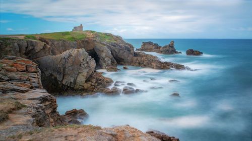 Scenic view of rocks in sea against sky