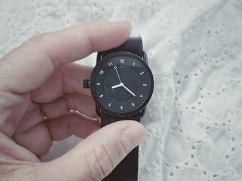 Close-up of hand holding clock against blurred background