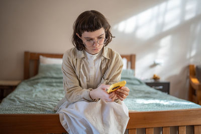 Portrait of young woman sitting on bed at home
