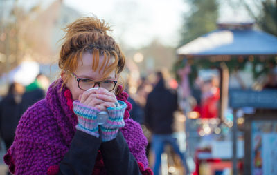 Portrait of woman drinking tea at market during winter