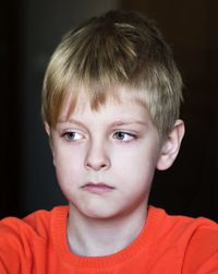 Close-up of sad boy against black background