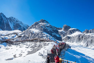 People on snowcapped mountain against blue sky