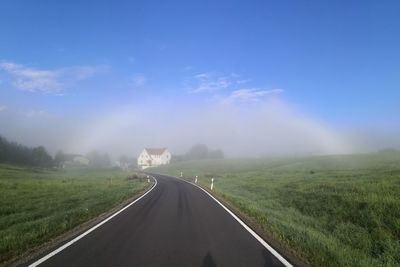 Road amidst field against sky