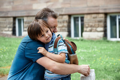 Dad hugs the child in front of the kindergarten or school. the beginning of the school year. 