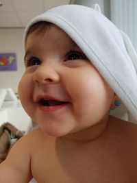 Close-up of happy shirtless baby covered with towel at home