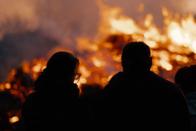 Rear view of silhouette people by fire at night