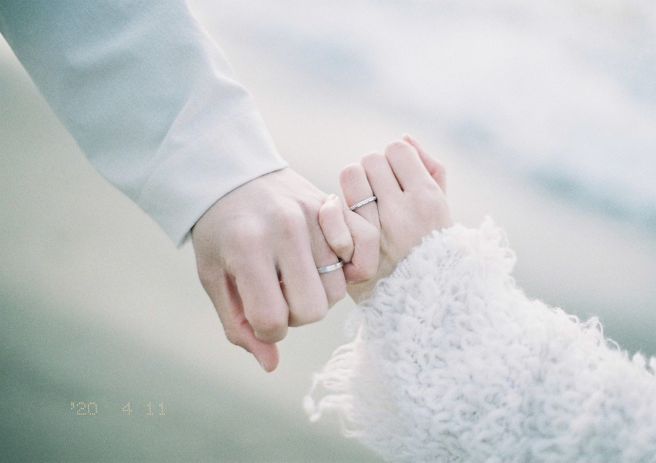 MIDSECTION OF COUPLE KISSING ON HAND HOLDING HANDS