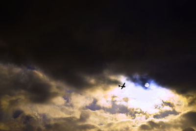 Low angle view of airplane flying against cloudy sky