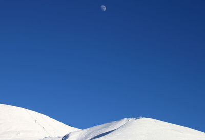 Scenic view of snow against clear blue sky