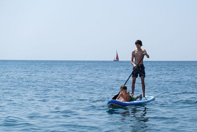 A young sports man with a child sails on a sup in the sea. healthy lifestyle concept