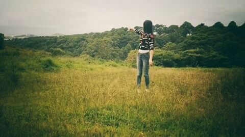 WOMAN STANDING ON GRASSY FIELD