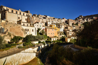 Buildings in city against clear blue sky