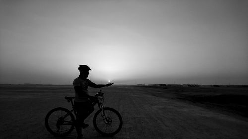 Man with bicycle on beach against sky