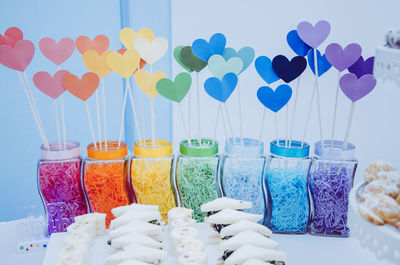 Close-up of multi colored umbrellas on glass against blue wall