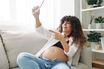 Side view of woman sitting on sofa at home