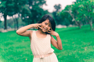 Portrait of a smiling young woman standing on field