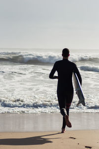 Rear view of man looking at sea against sky