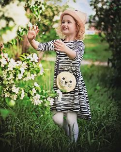 Smiling girl holding plants on grassy field at park