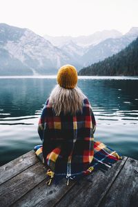 Rear view of woman looking at lake against mountain range