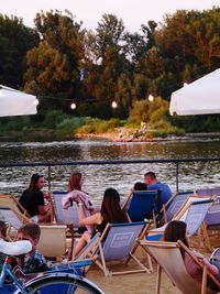 People sitting on boat in lake against trees