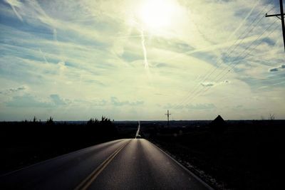 Road amidst silhouette landscape against sky